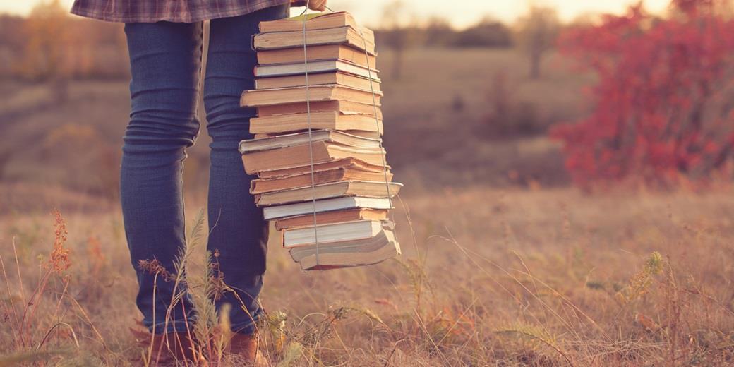A woman holding a pile of books