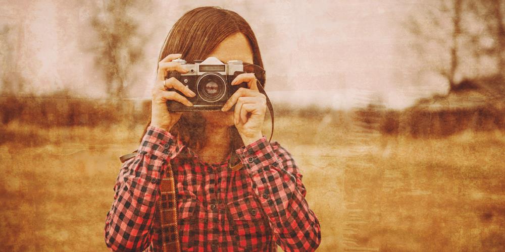 Woman pointing a camera at you