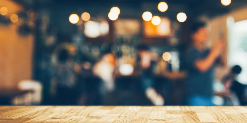 Wooden table and a blurry view of people hanging out